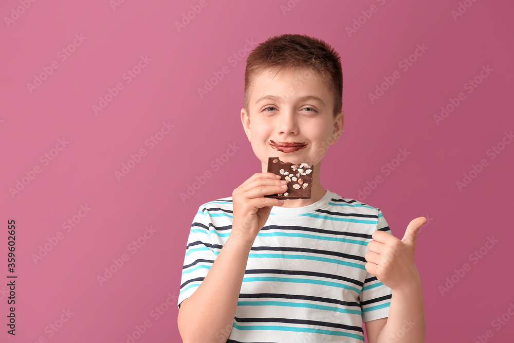 Cute little boy with chocolate showing thumb-up on color background Cute little boy with chocolate showing thumb-up on color background