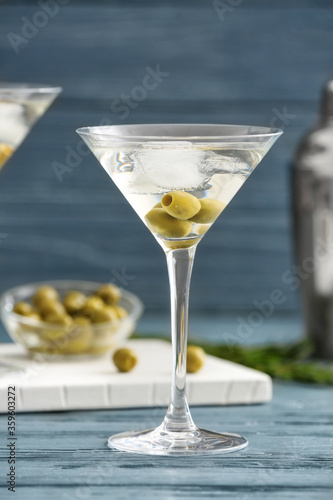 Glass of tasty martini cocktail with olives on table