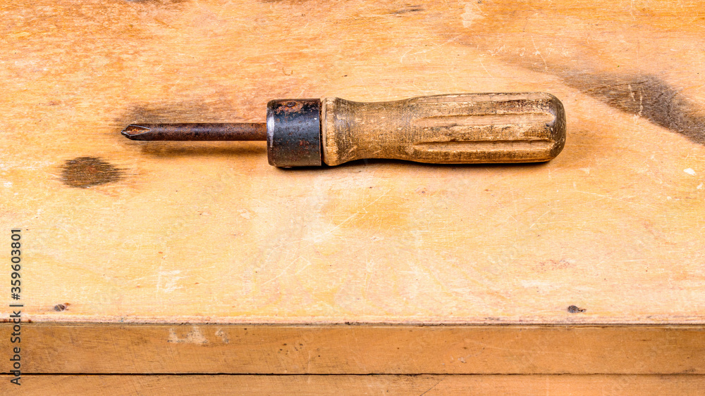 An old Soviet-era screwdriver on the background of a plywood tool box