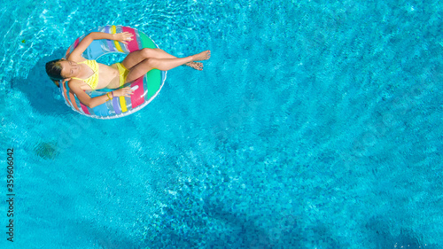 Acrive girl in swimming pool aerial top view from above  kid swims on inflatable ring donut   child has fun in blue water on family vacation resort 