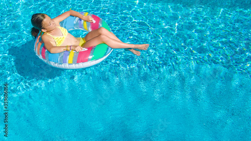 Acrive girl in swimming pool aerial top view from above  kid swims on inflatable ring donut   child has fun in blue water on family vacation resort 