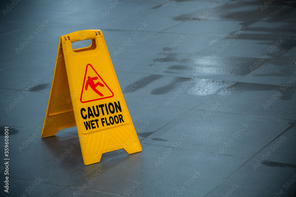 Yellow wet floor caution sign during rain with puddle of water when floor is slippery and copy space for text
 - obrazy, fototapety, plakaty 