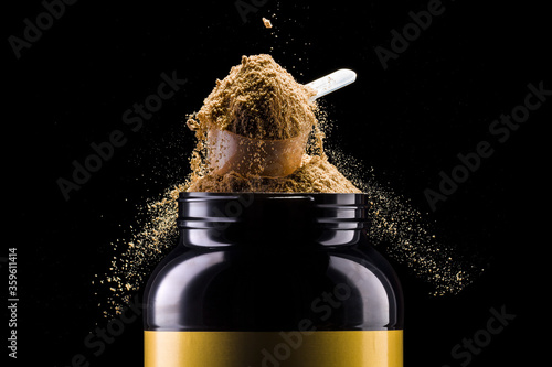 A scoop of chocolate protein powder drink in black plastic container isolated