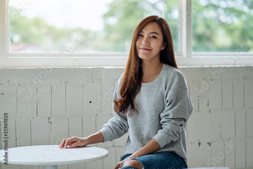 Obraz na plátně Portrait image of a beautiful young asian woman sitting in cafe with feeling hap
