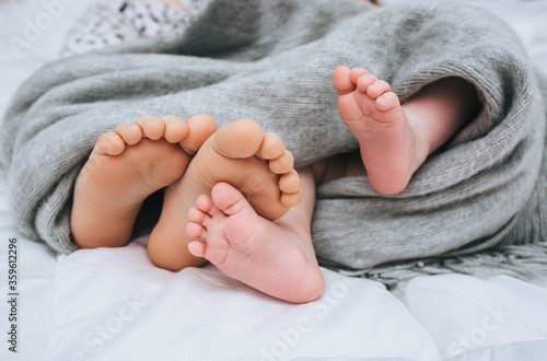 A small child and his sister, mom sleep on a white bed, covered with a gray plaid close-up. The legs of the newborn and parents. Photography, concept.