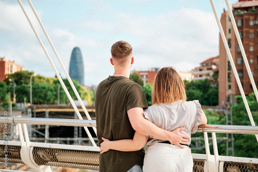 happy young couple, a handsome man and a curvy model, in a bridge looking at Barcelona skyline happy young couple, a handsome man and a curvy model, in a bridge looking at Barcelona skyline