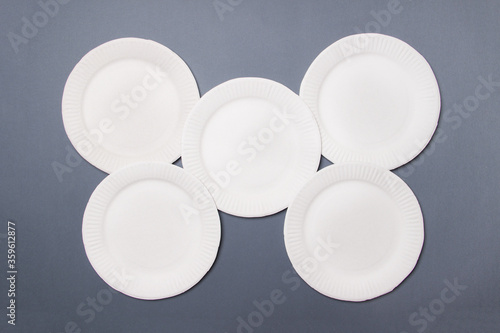 five white eco-friendly plates lie on gray colored paper background. Top view. Mock-up