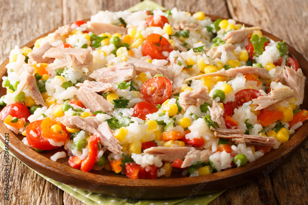 Cooked rice with tuna, tomatoes, sweet pepper, corn, green peas and herbs close-up in a plate on the table. horizontal Cooked rice with tuna, tomatoes, sweet pepper, corn, green peas and herbs close-up in a plate on the table. horizontal