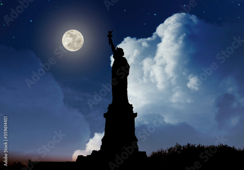 Silhouette of Statue of Liberty over dramatic full moon, New York, USA