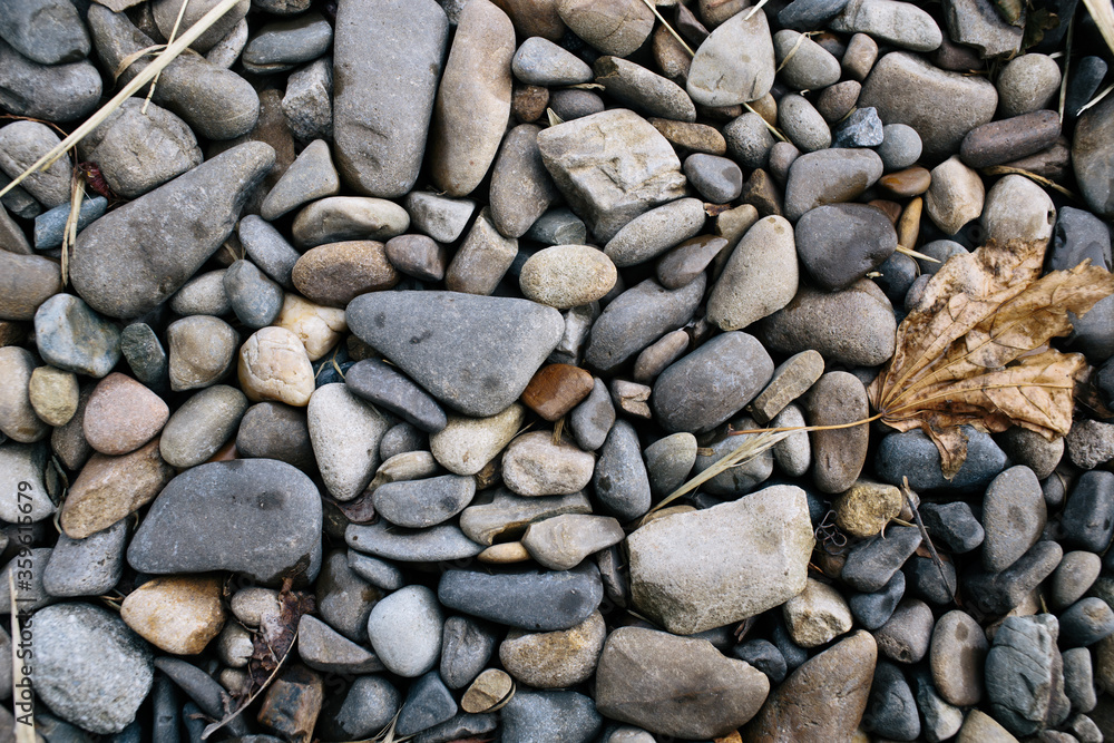 Many small stones. Beach with stones and green grass. Pebble stones. Many small stones. Beach with stones and green grass. Pebble stones.