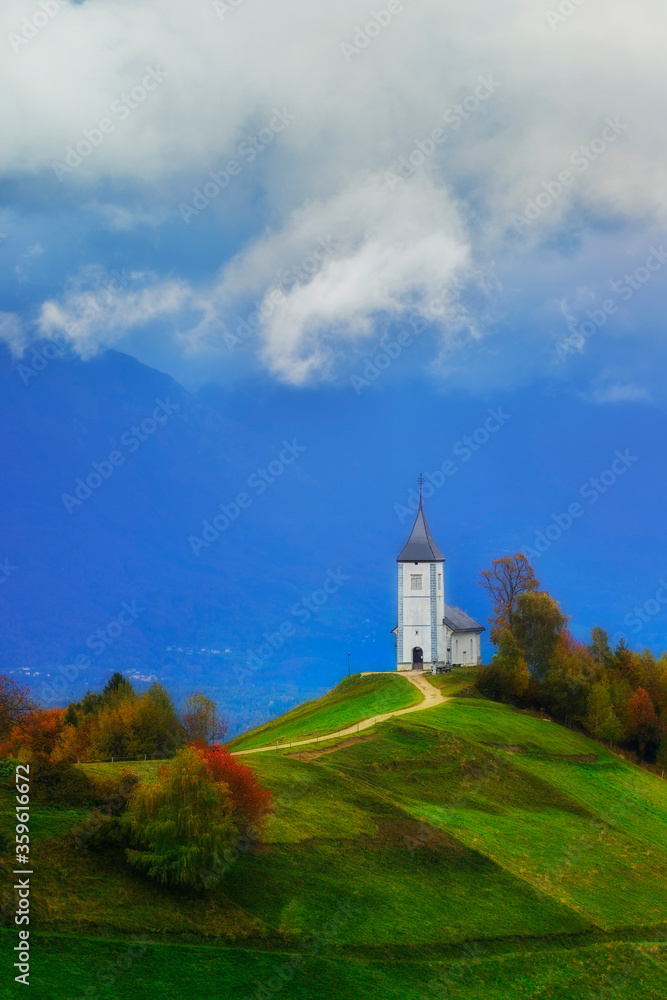 Fototapeta premium St Primoz church in Slovenia under deep blue sky with big white clouds