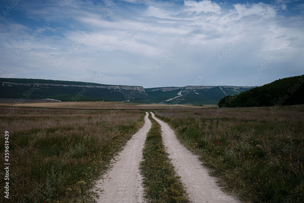 Dirt road among the spring field. Before the storm Dirt road among the spring field. Before the storm