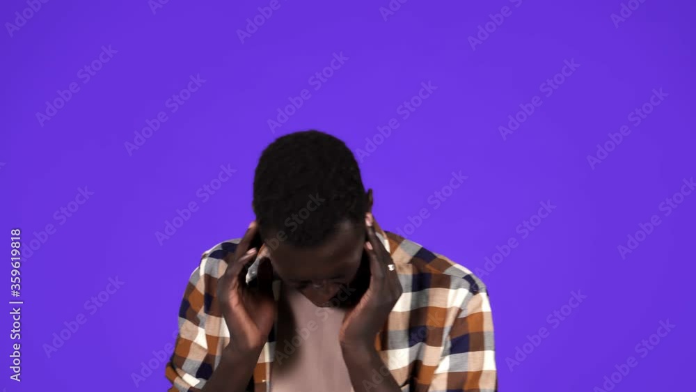 Pleased Afro American man enjoys perfect loud sound in new earphones, dressed in plaid shirt, has free time, entertains himeslf with music. Sings loudly Pleased Afro American man enjoys perfect loud sound in new earphones, dressed in plaid shirt, has free time, entertains himeslf with music. Sings loudly