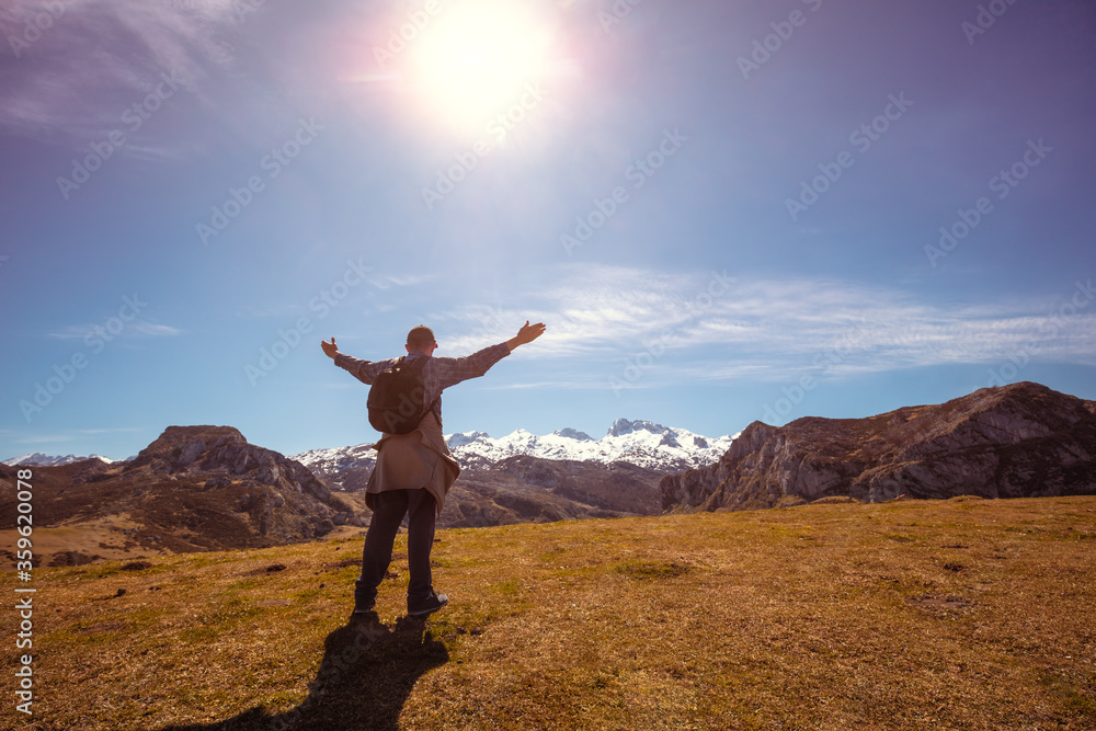 A man with hands in the air on the top of mount looks at beautiful panorama of the mountains. National Park Peaks of Europe. Cantabria, Spain, Europe
