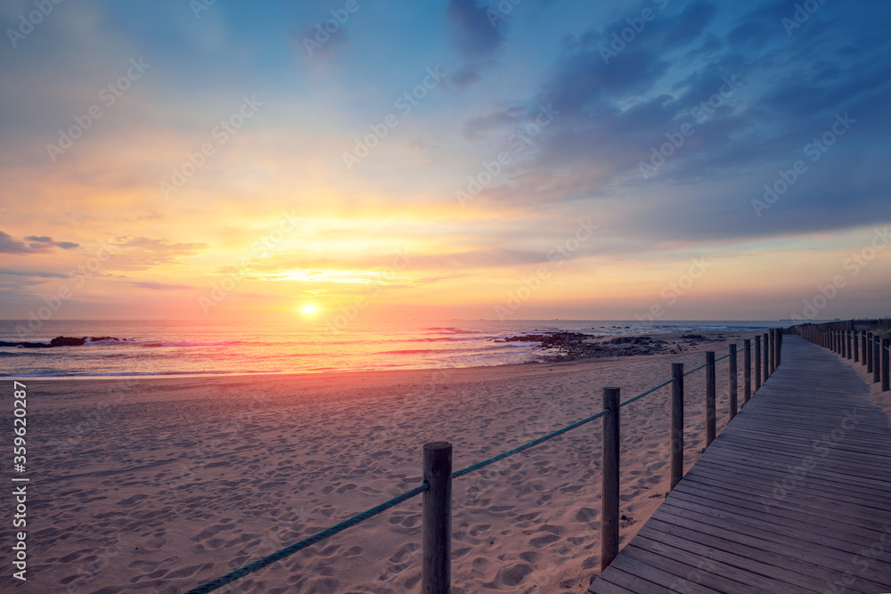 Wooden walkway on the sandy beach at magical sunset light. Beautiful seascape in the evening Wooden walkway on the sandy beach at magical sunset light. Beautiful seascape in the evening