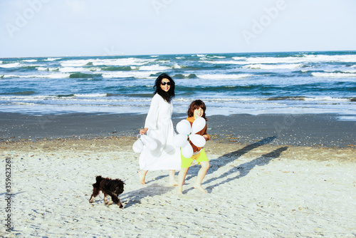 Joyful mom and son running on the beach with balloons photo