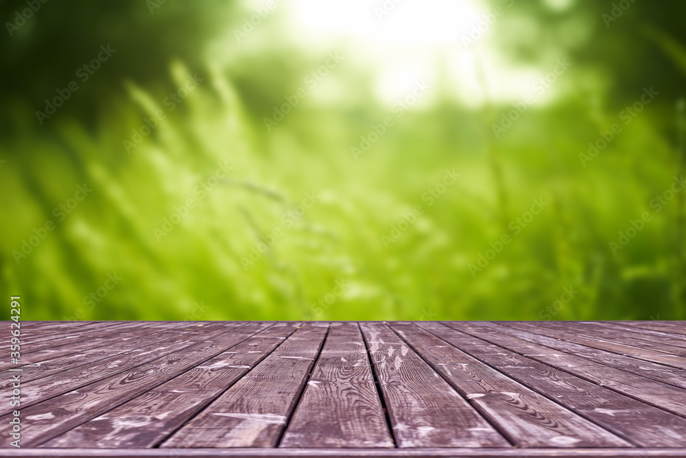 Fototapeta premium Mockup. Empty wooden deck table with foliage bokeh background.