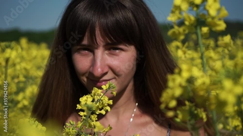 Young beautiful girl in field of yellow flowers.Portrait of a young girl.Beautiful girl smile.Rapeseed field