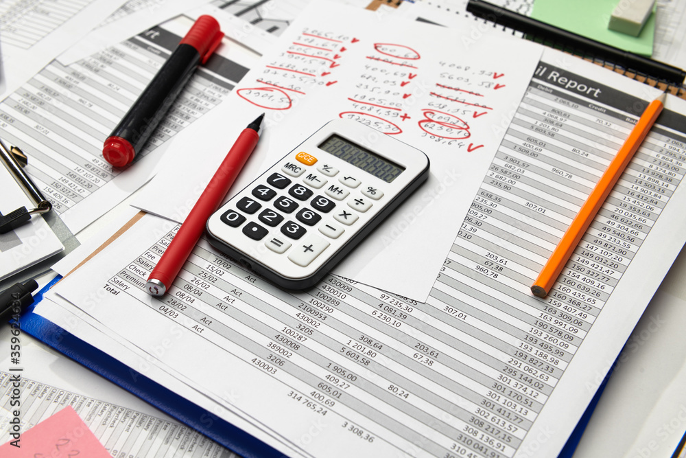 Top view of office employee's desk - work with financial reports, analysis and accounting, tables and graphs, various office items for bookkeeping Top view of office employee's desk - work with financial reports, analysis and accounting, tables and graphs, various office items for bookkeeping