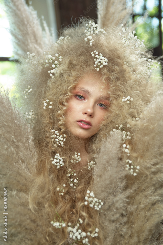 A beautiful girl with lush, long, curly hair. There are white flowers in her brown hair. High-resolution photos A beautiful girl with lush, long, curly hair. There are white flowers in her brown hair. High-resolution photos