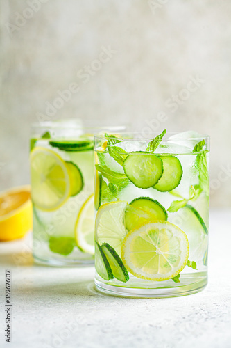 Detox sassy water with cucumber and lemon in glass, light background. Healthy eating concept.