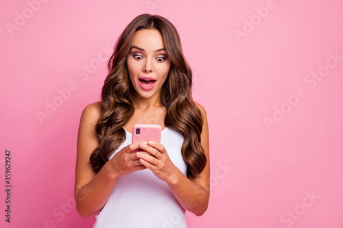 Photo of pretty wavy lady open mouth hold telephone hands chatting friends reading positive comments blog good mood wear white casual singlet isolated pink color background