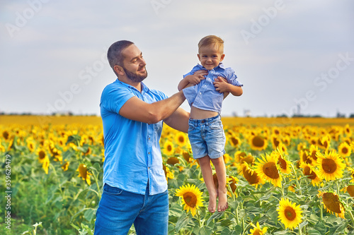 Happy father and son on a summer walk in the field with sunflowers . Father's day