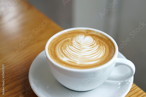 Hot Latte - A cup of coffee with milk and beautiful leaf pattern latte art on wooden table and copy space, Perfect for breakfast time.