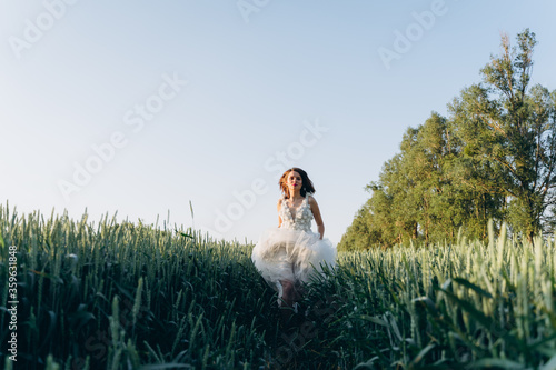 attractive woman wearing veil and long white dress standing in the field