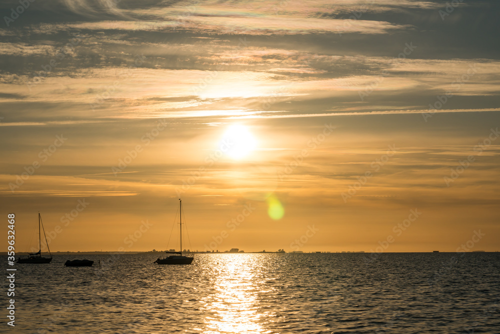 Beautiful yellow sunset with the ocean and sailing boats in the forground