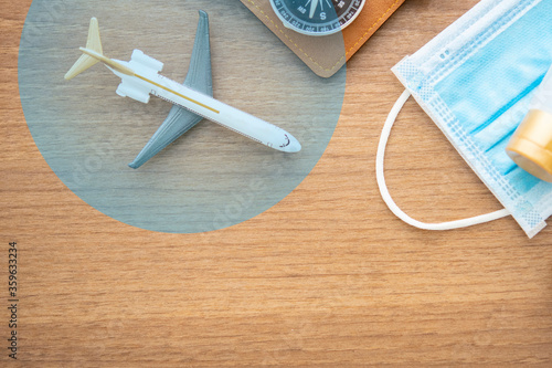 top view of travel item and airplane in the bubble with face mask  and wallet on wooden business desk, travel bubble concept