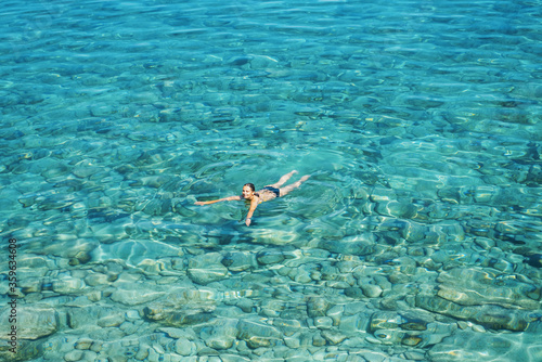 A woman swims in blue sea water in the bay. Nature and relaxation  top view