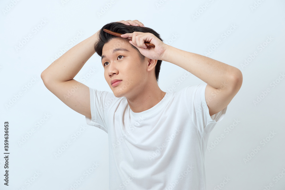 Portrait of handsome cheerful young man combing his hair Portrait of handsome cheerful young man combing his hair