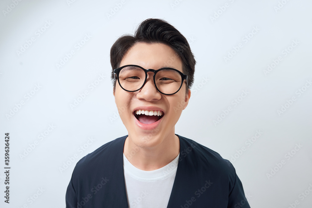 Portrait of funny young Asian man laughing hard with big open mouth, over white background