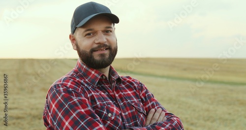 Close up of the Caucasian agricultural businessman in a hat standing in the field during harvest season. Portrait. © VAKSMANV