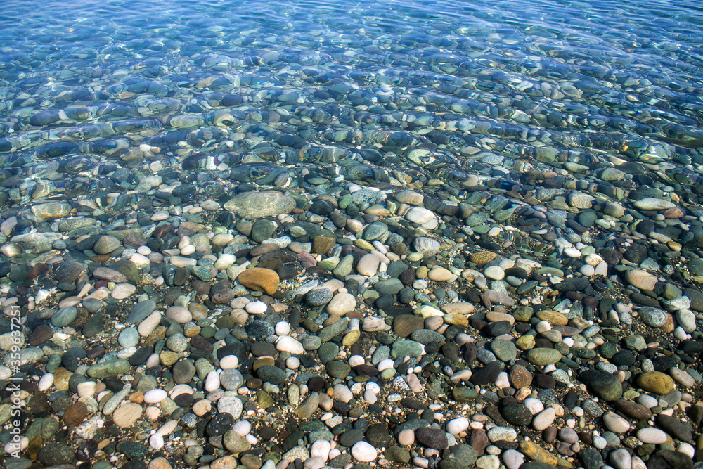 Sea stones in sea water. Pebbles under water. The view from the top. Nautical background. Clean sea water. Transparent sea