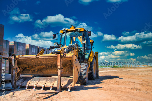 Bulldozer against the background of the solar station which is being built.