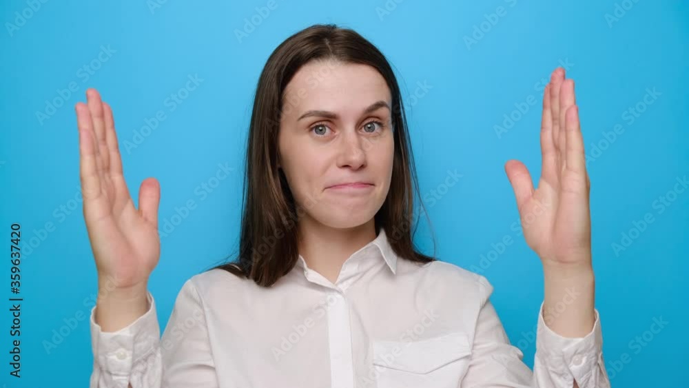 Surprised young woman isolated on blue studio background showing big size gesture with hands