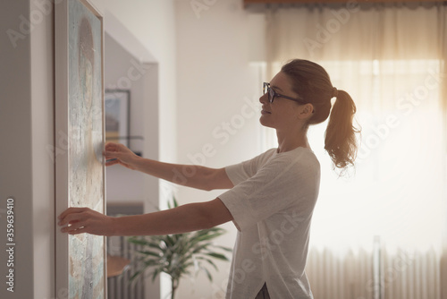 Woman hanging a painting at home photo