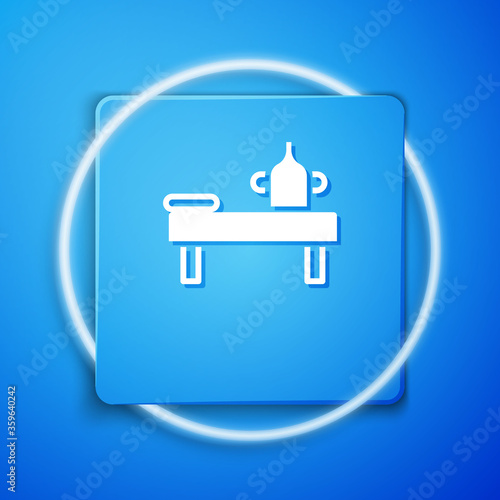 White Massage table with oil icon isolated on blue background. Blue square button. Vector.
