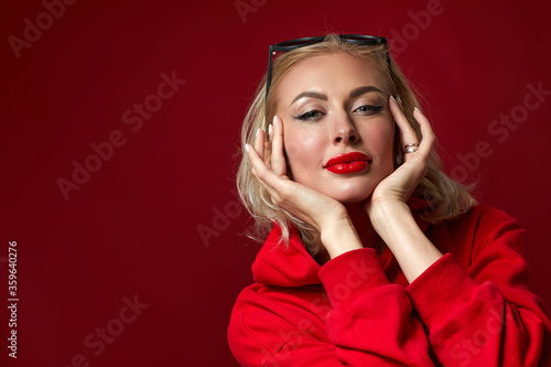 gorgeous blonde woman with sunglasses on red background. copy space for text