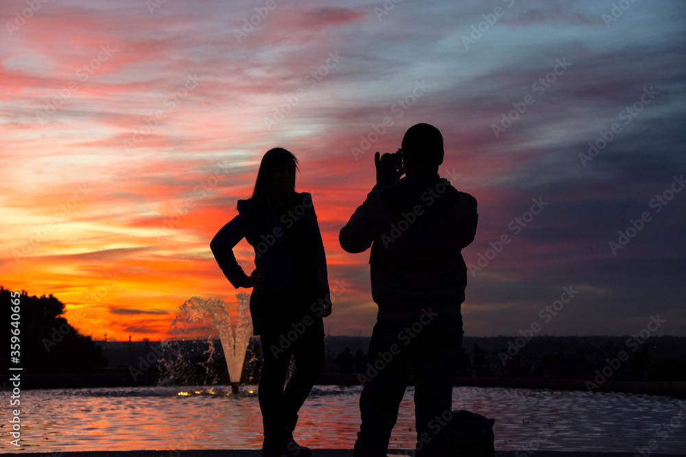 silhouette of a man holding a cellphone taking pictures outside during sunrise or sunset. Madrid