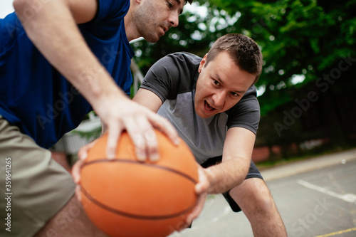 Two young men playing basketball in the park. Friends having a friendly match outdoors 