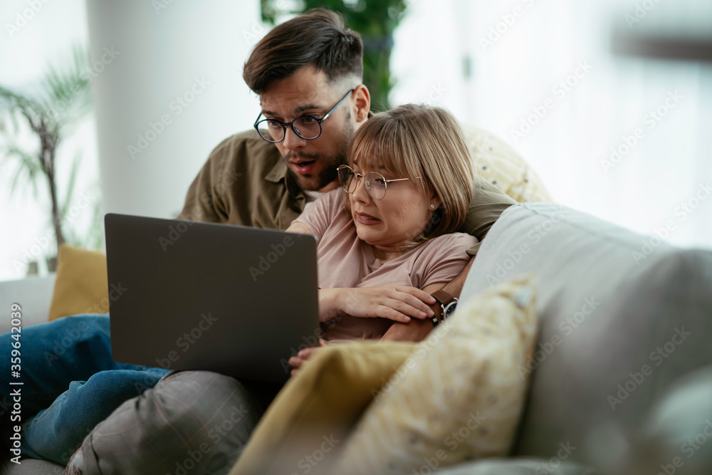 Young couple watching movie on lap top. Loving couple enjoying at home.	