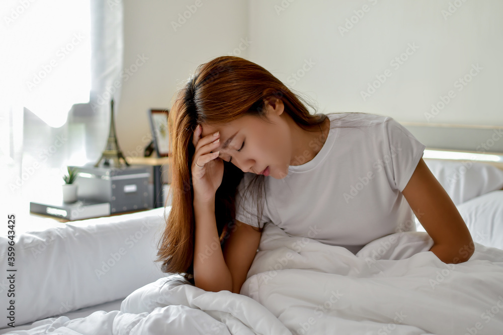 An Asian woman feels headache. She wakes up in the middle of the night while she sleeps in bed. An Asian woman feels headache. She wakes up in the middle of the night while she sleeps in bed.