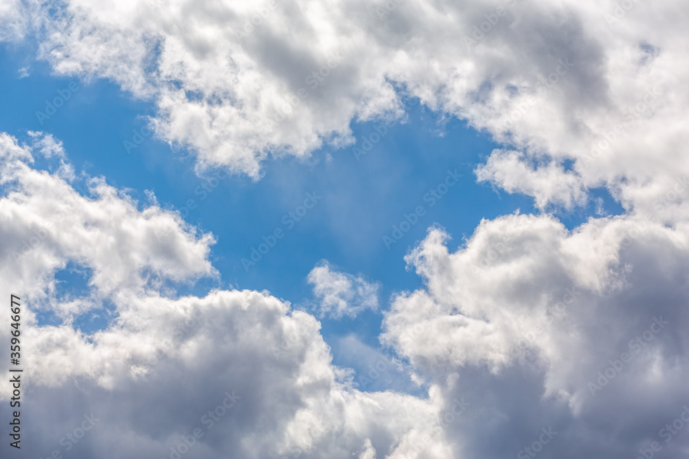 fluffy white clouds against a blue sky backlit by the sun fluffy white clouds against a blue sky backlit by the sun