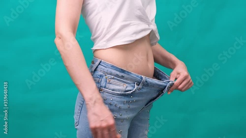 Attractive young woman wearing jeans and showing slim body after sport trainings and healthy eating. Weight loss concept.