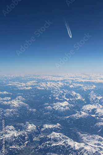 Widok z samolotu na góry Alpejskie. Śnieg na górach gór. Na horyzoncie ślady od innego samolotu.