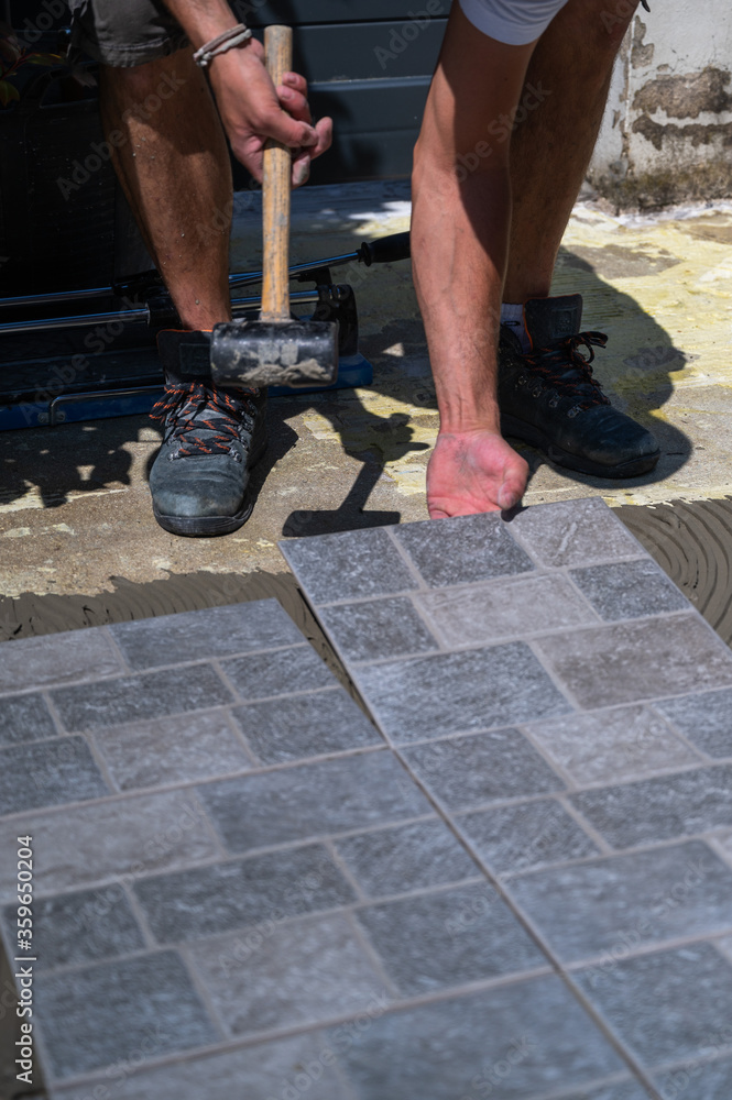 Gros plan sur un travailleur posant une dalle de carrelage Gros plan sur un travailleur posant une dalle de carrelage