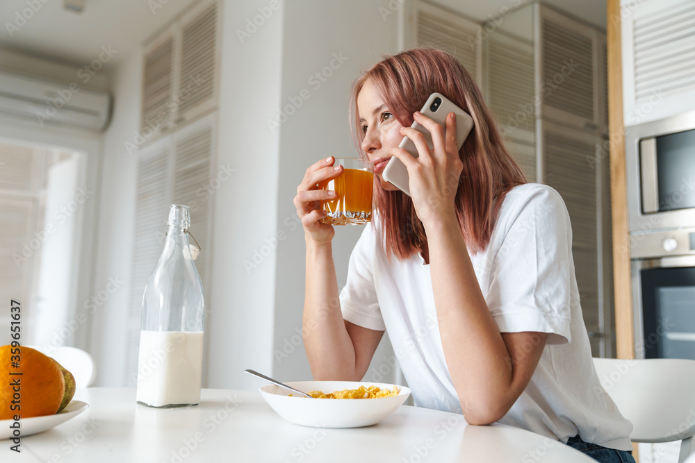 Photo of young nice woman talking on cellphone while having breakfast Photo of young nice woman talking on cellphone while having breakfast
